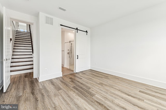 unfurnished bedroom featuring a closet, a barn door, and light hardwood / wood-style flooring