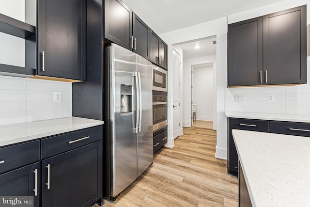 kitchen featuring light stone countertops, light hardwood / wood-style flooring, appliances with stainless steel finishes, and tasteful backsplash