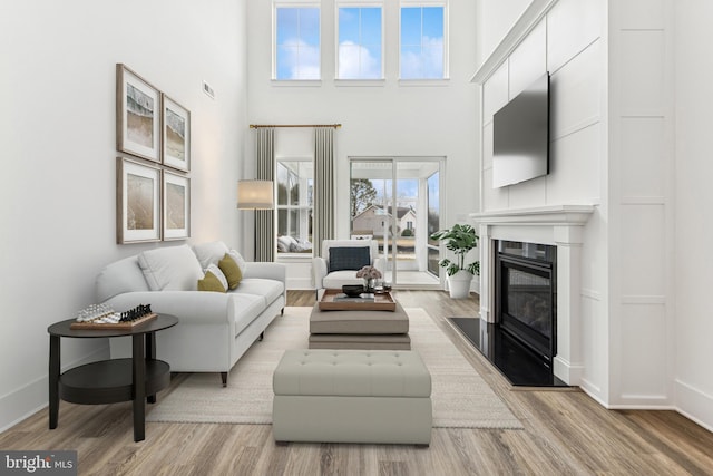 living room featuring light wood-type flooring and a high ceiling