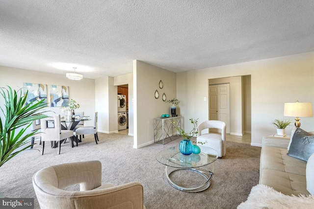 carpeted living room featuring a textured ceiling and stacked washer and dryer