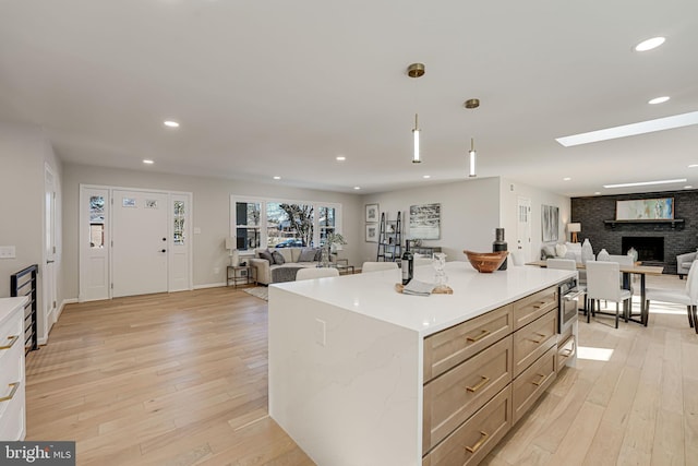 kitchen with light stone counters, decorative light fixtures, a center island, and light hardwood / wood-style floors