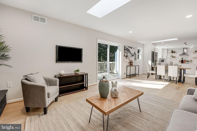 living room with a skylight and light hardwood / wood-style floors