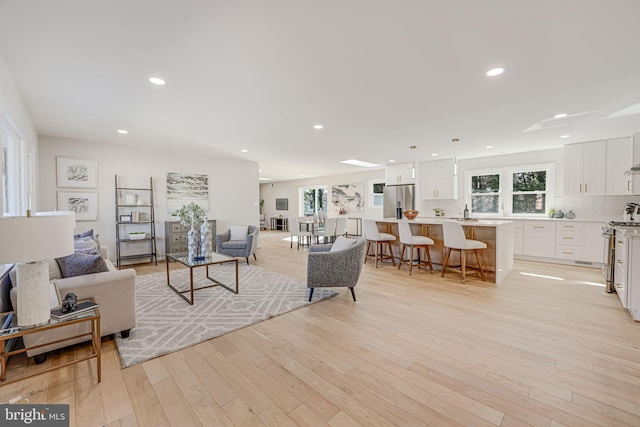 living room featuring sink and light hardwood / wood-style flooring