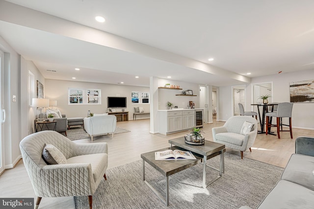 living room featuring bar, beverage cooler, and light hardwood / wood-style flooring