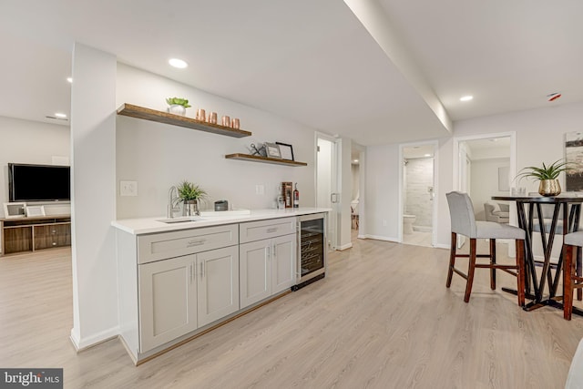 bar featuring wine cooler, sink, and light hardwood / wood-style floors