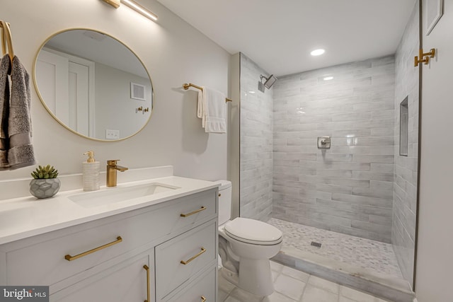 bathroom with vanity, tile patterned floors, toilet, and tiled shower