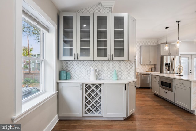 kitchen with stainless steel appliances, hanging light fixtures, dark wood-type flooring, and backsplash