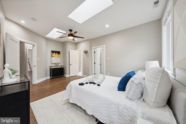 bedroom with multiple windows, dark hardwood / wood-style flooring, ceiling fan, and a skylight