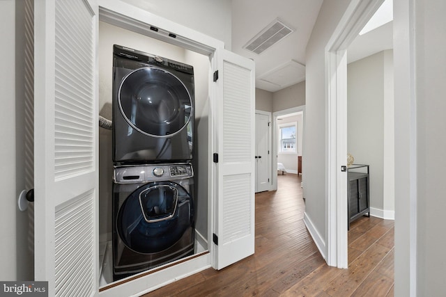 laundry area featuring stacked washer / drying machine and dark hardwood / wood-style floors