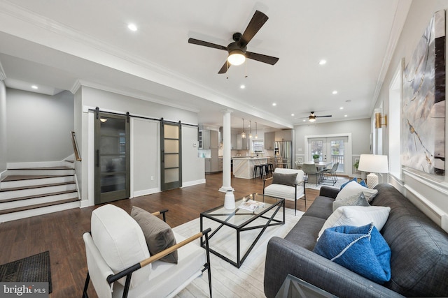 living room with hardwood / wood-style flooring, ceiling fan, a barn door, and crown molding