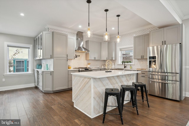 kitchen with pendant lighting, wall chimney range hood, gray cabinetry, and appliances with stainless steel finishes