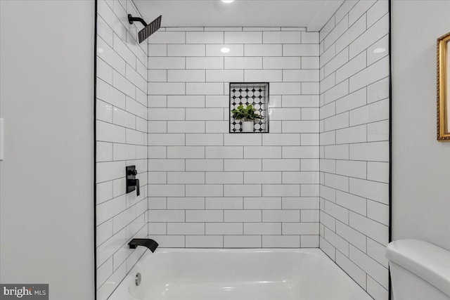 bathroom featuring toilet and tiled shower / bath