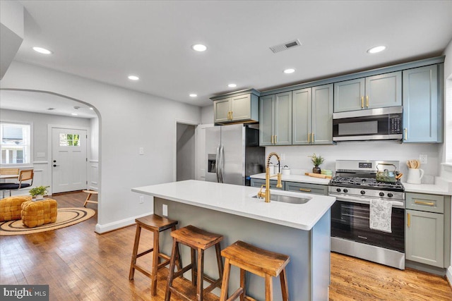 kitchen with an island with sink, sink, a kitchen breakfast bar, light hardwood / wood-style floors, and stainless steel appliances