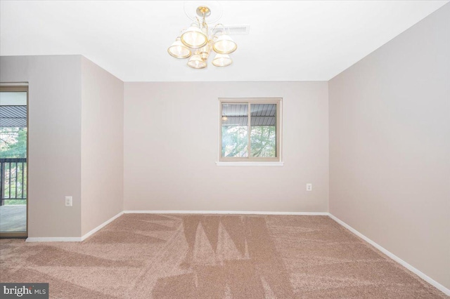 carpeted spare room with an inviting chandelier