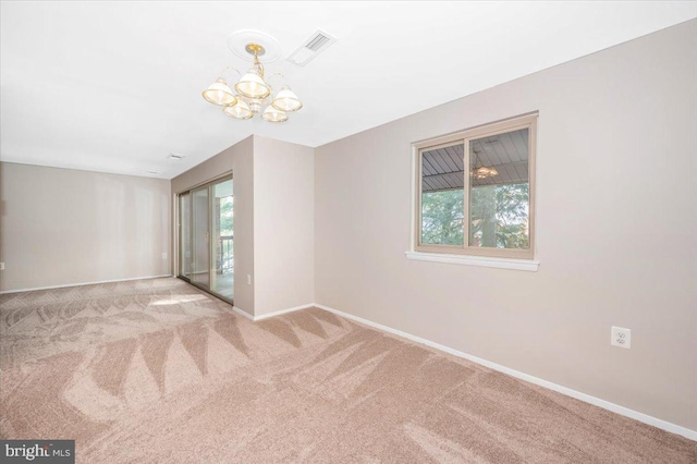 unfurnished room with light carpet, a healthy amount of sunlight, and a notable chandelier