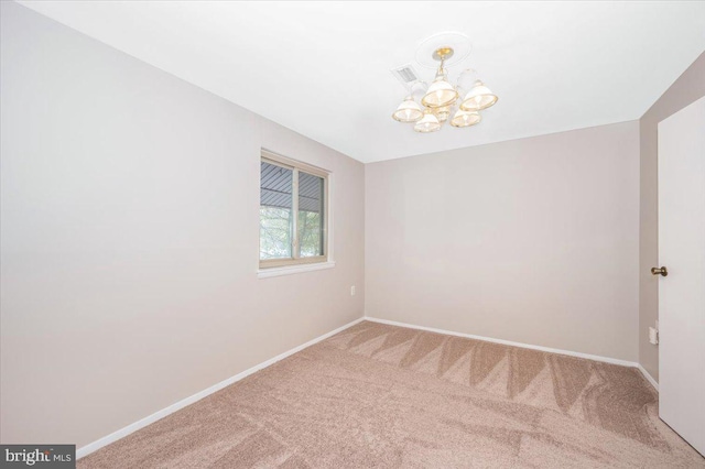 spare room with carpet floors and a notable chandelier