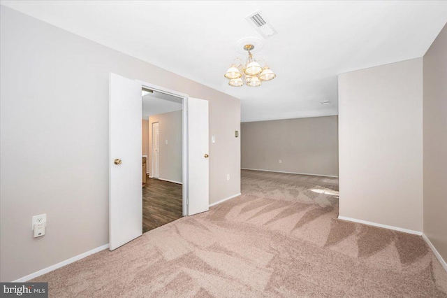 empty room with a notable chandelier and carpet