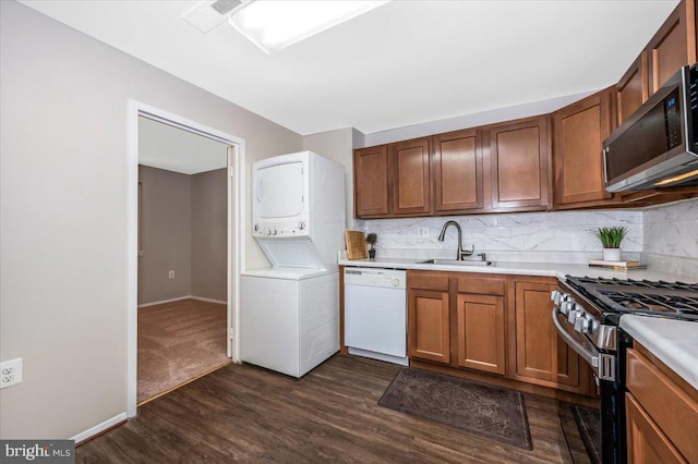 kitchen featuring dark hardwood / wood-style flooring, sink, appliances with stainless steel finishes, tasteful backsplash, and stacked washing maching and dryer