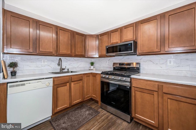 kitchen with sink, stainless steel appliances, dark wood-type flooring, and backsplash