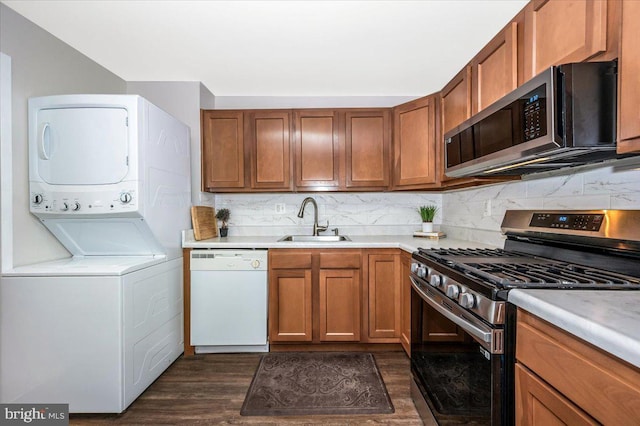 kitchen featuring sink, backsplash, stacked washer and clothes dryer, dark hardwood / wood-style floors, and stainless steel appliances