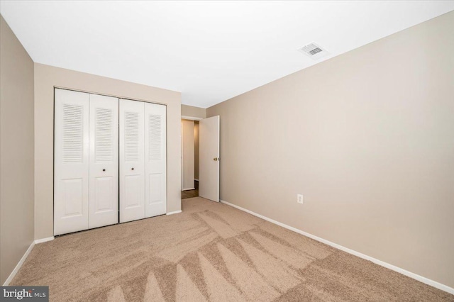 unfurnished bedroom featuring light colored carpet and a closet