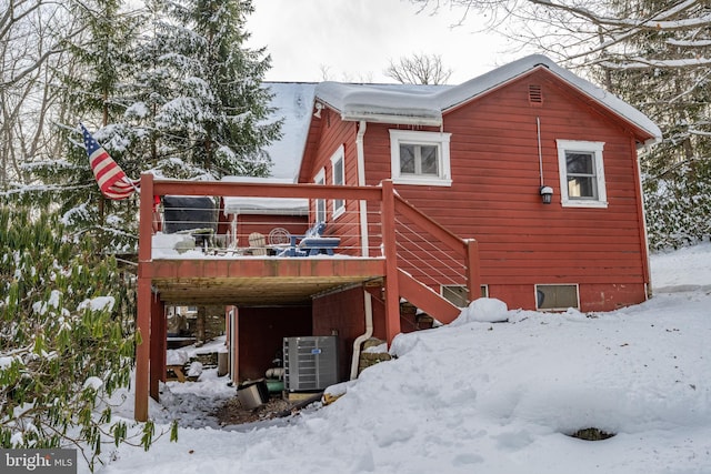 snow covered house with cooling unit and a wooden deck