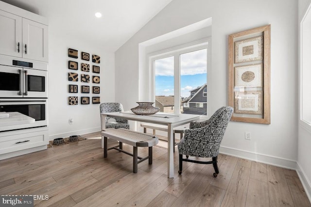 dining room featuring light wood-type flooring and lofted ceiling