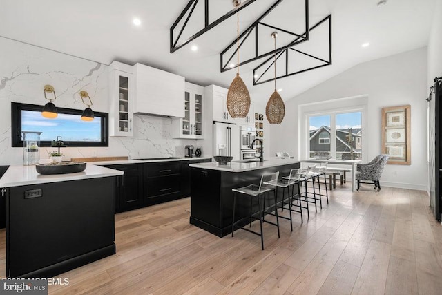 kitchen featuring white cabinetry, a center island with sink, tasteful backsplash, and a kitchen bar