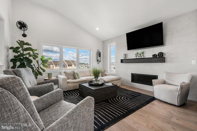 living room featuring a tile fireplace, hardwood / wood-style flooring, and high vaulted ceiling