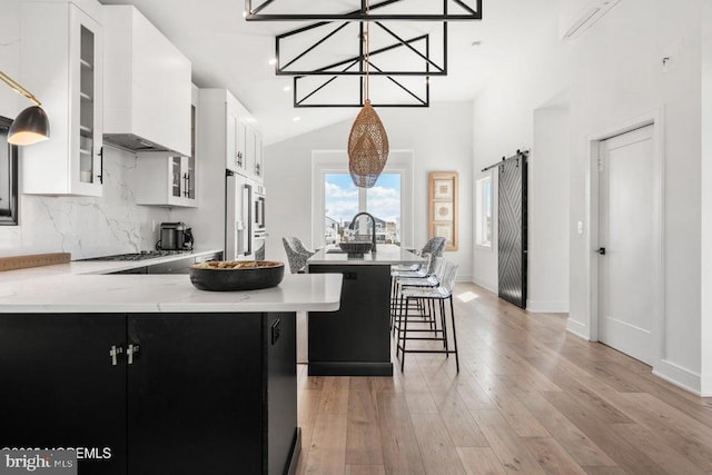 kitchen featuring a kitchen island, white cabinetry, decorative backsplash, premium range hood, and light wood-type flooring