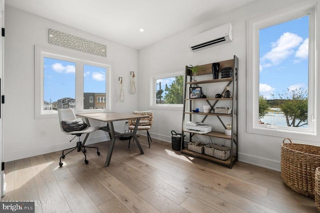 office space with an AC wall unit and light hardwood / wood-style floors