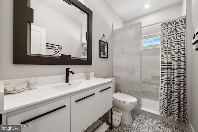 bathroom featuring vanity, toilet, and a tile shower