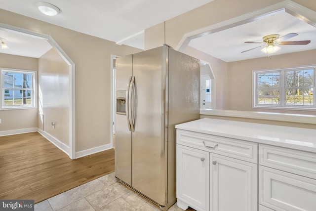 kitchen featuring stainless steel refrigerator with ice dispenser, white cabinetry, a wealth of natural light, and light tile patterned floors