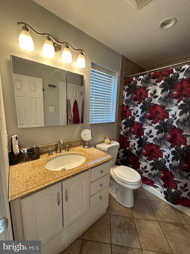 bathroom with toilet, vanity, and tile patterned flooring