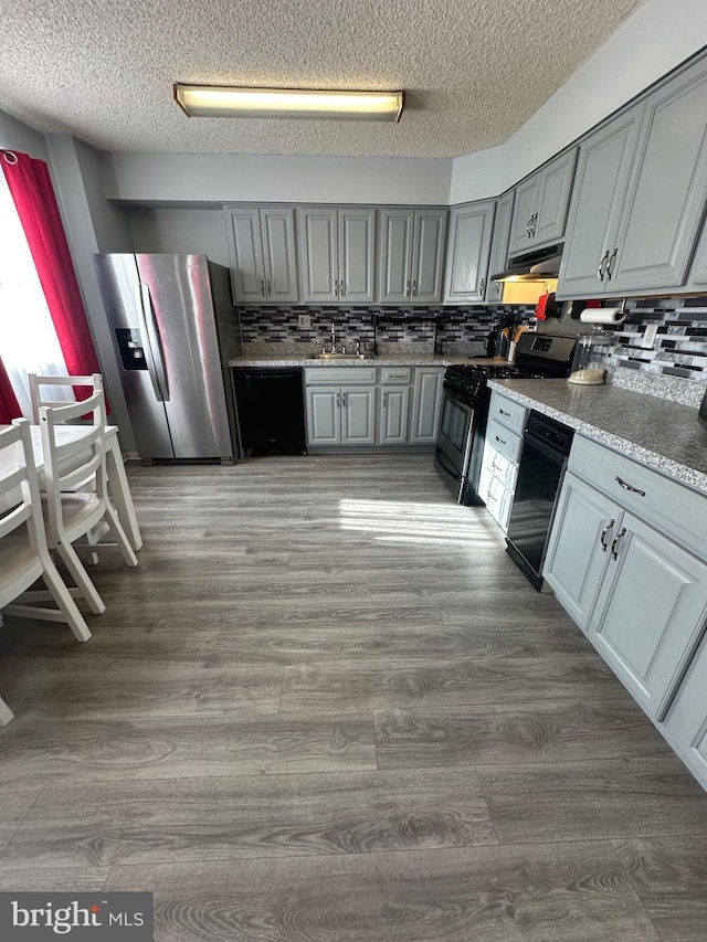 kitchen featuring gray cabinets, black dishwasher, stainless steel fridge with ice dispenser, and gas stove