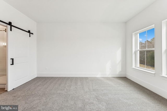 unfurnished room with carpet flooring and a barn door