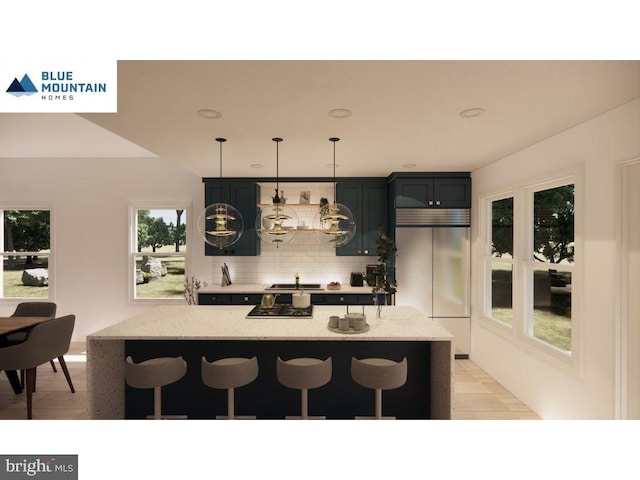 kitchen with fridge, a kitchen breakfast bar, light stone counters, and hanging light fixtures