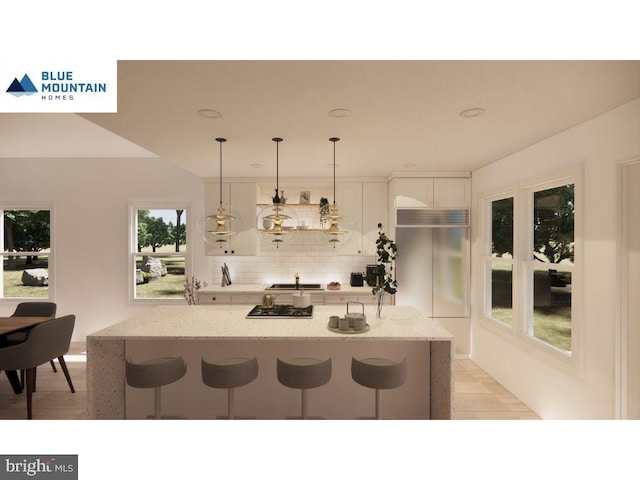 kitchen with light stone counters, built in refrigerator, a breakfast bar, and white cabinets