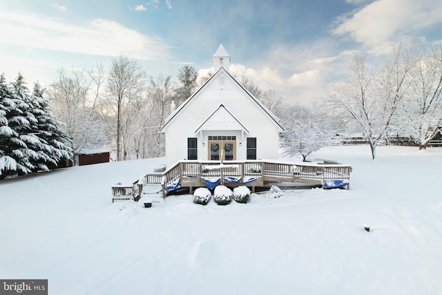 snow covered back of property featuring a wooden deck and french doors