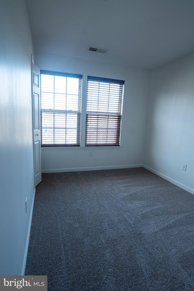 empty room featuring a healthy amount of sunlight and dark colored carpet