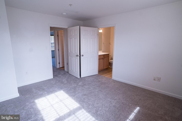 unfurnished bedroom featuring ensuite bathroom and light carpet