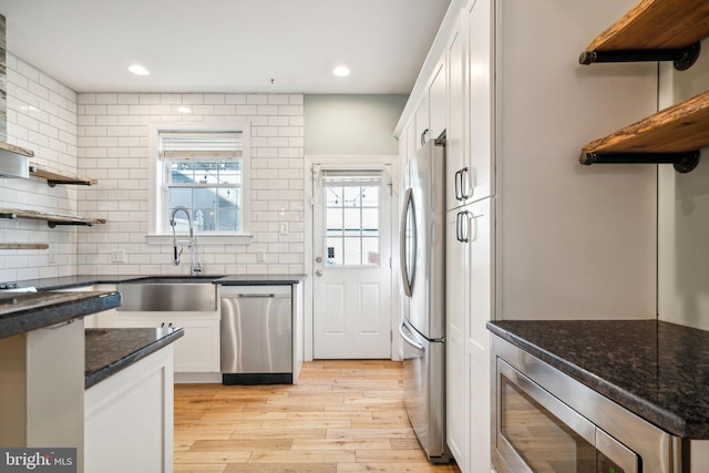 kitchen featuring sink, appliances with stainless steel finishes, white cabinetry, tasteful backsplash, and light wood-type flooring