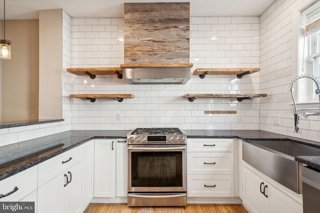 kitchen with appliances with stainless steel finishes, sink, white cabinets, backsplash, and dark stone counters