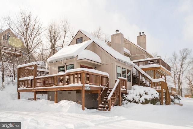 snow covered back of property with a wooden deck