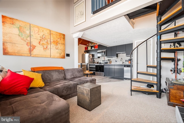 living room featuring sink, a towering ceiling, and light carpet