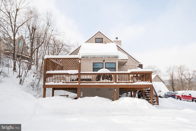 snow covered rear of property with a wooden deck