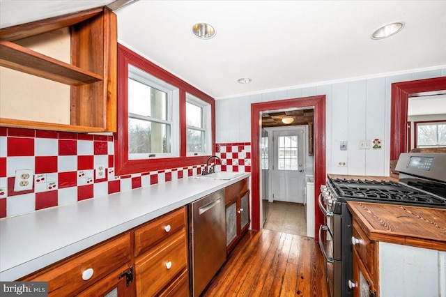 kitchen featuring crown molding, appliances with stainless steel finishes, sink, and dark hardwood / wood-style flooring