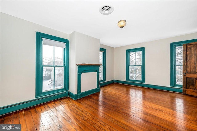 unfurnished living room with hardwood / wood-style flooring and a baseboard heating unit