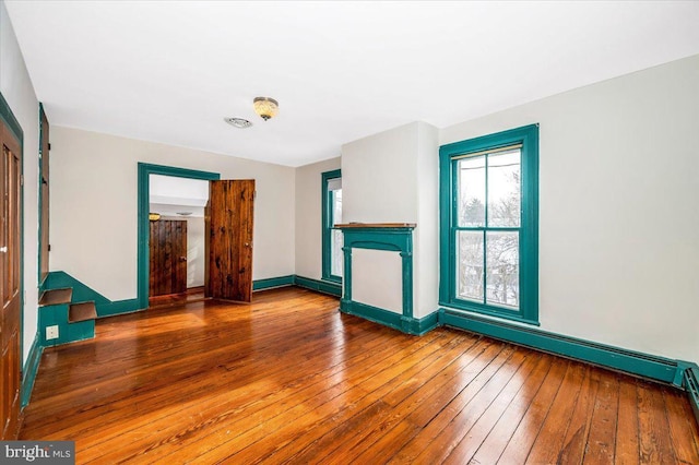 empty room with a baseboard heating unit and wood-type flooring