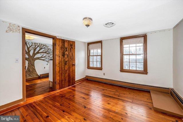 unfurnished bedroom with wood-type flooring and baseboard heating